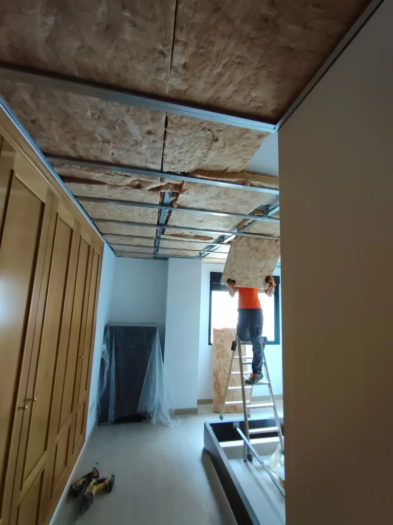 En la imagen una persona del equipo de DRUM está colocando lana de roca en el techo para hacer un aislamiento en una vivienda de Villarreal