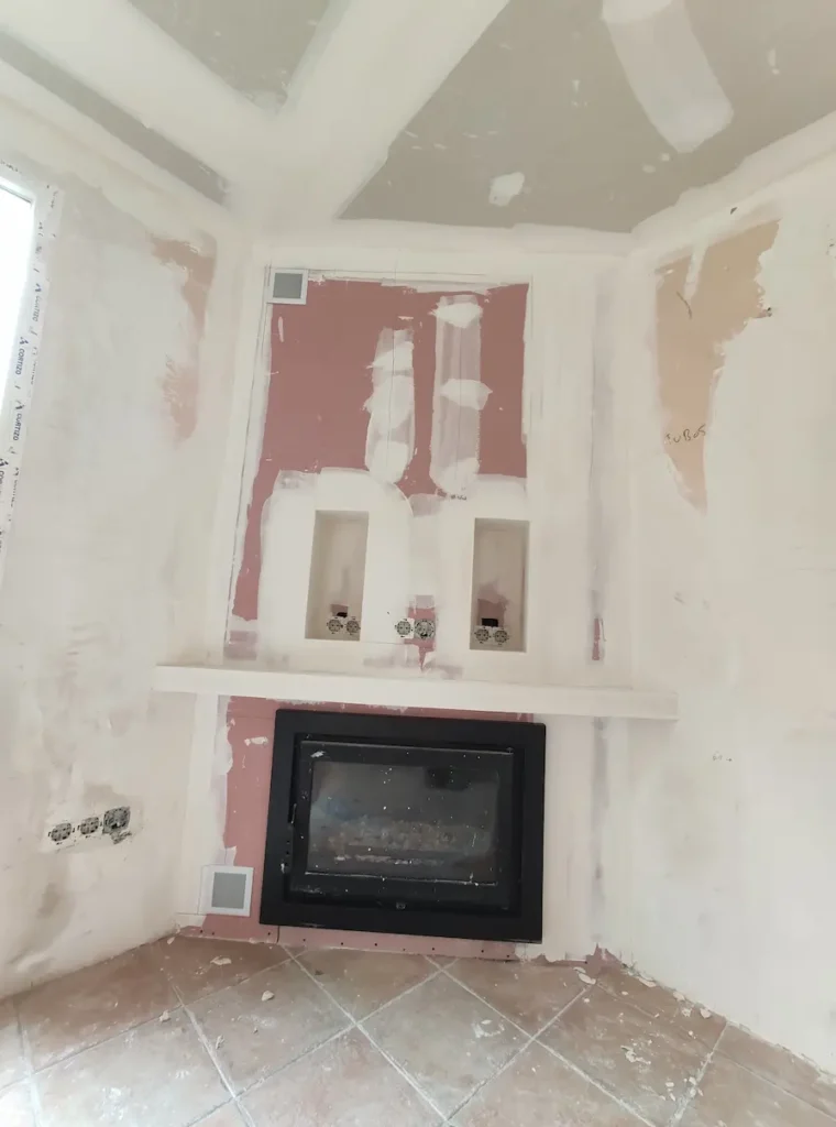 En la imagen vemos un mueble de pladur con estufa insert de leña y espacio para la tv hecho en una vivienda unifamiliar de Onda